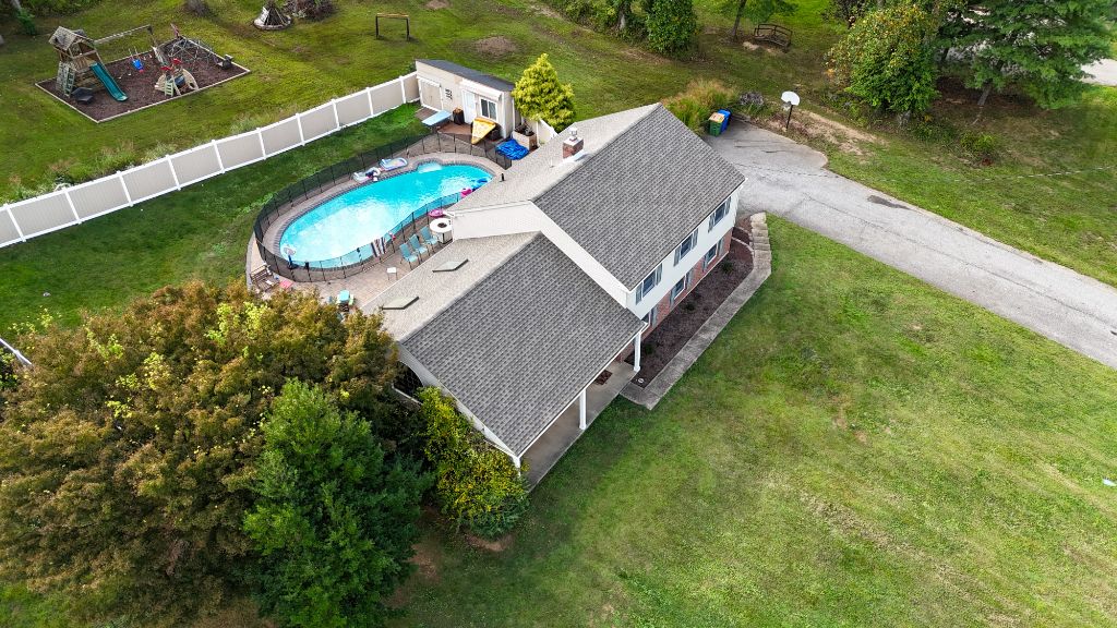 Aerial view of brick colonial home with new roof and inground pool