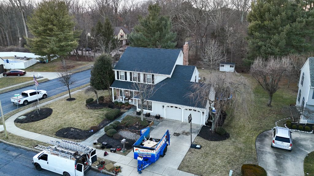 Aerial view of completed dark roof on white colonial during winter